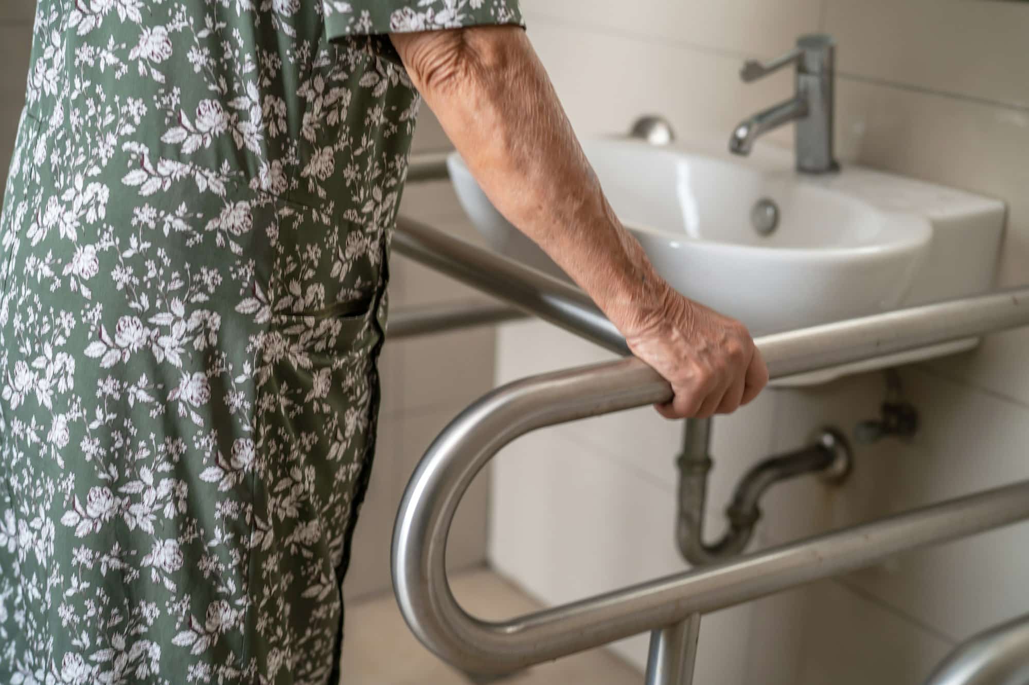 Asian elderly woman patient use toilet bathroom handle security.